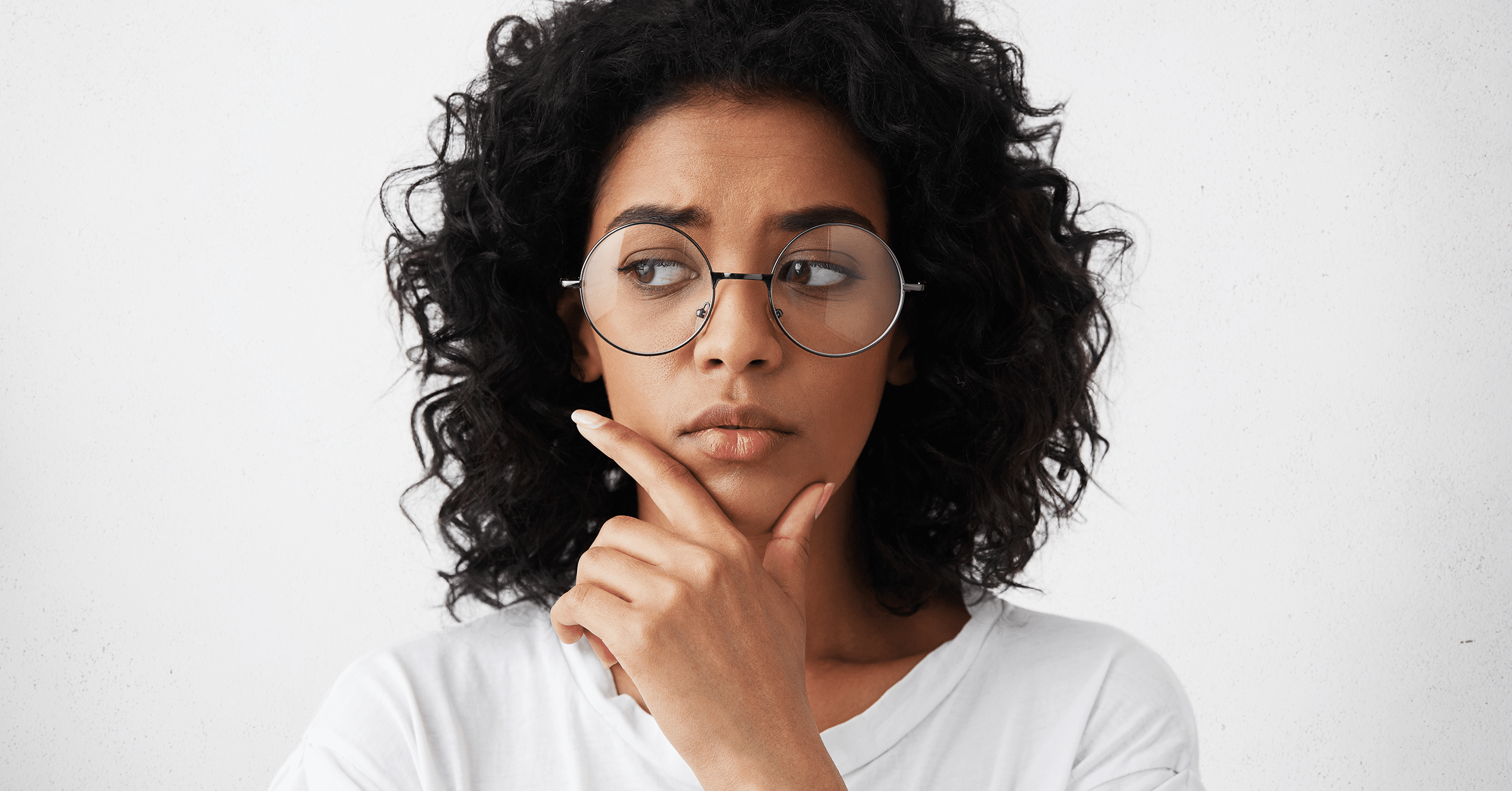 woman holds her chin and looks off to the side, thinking