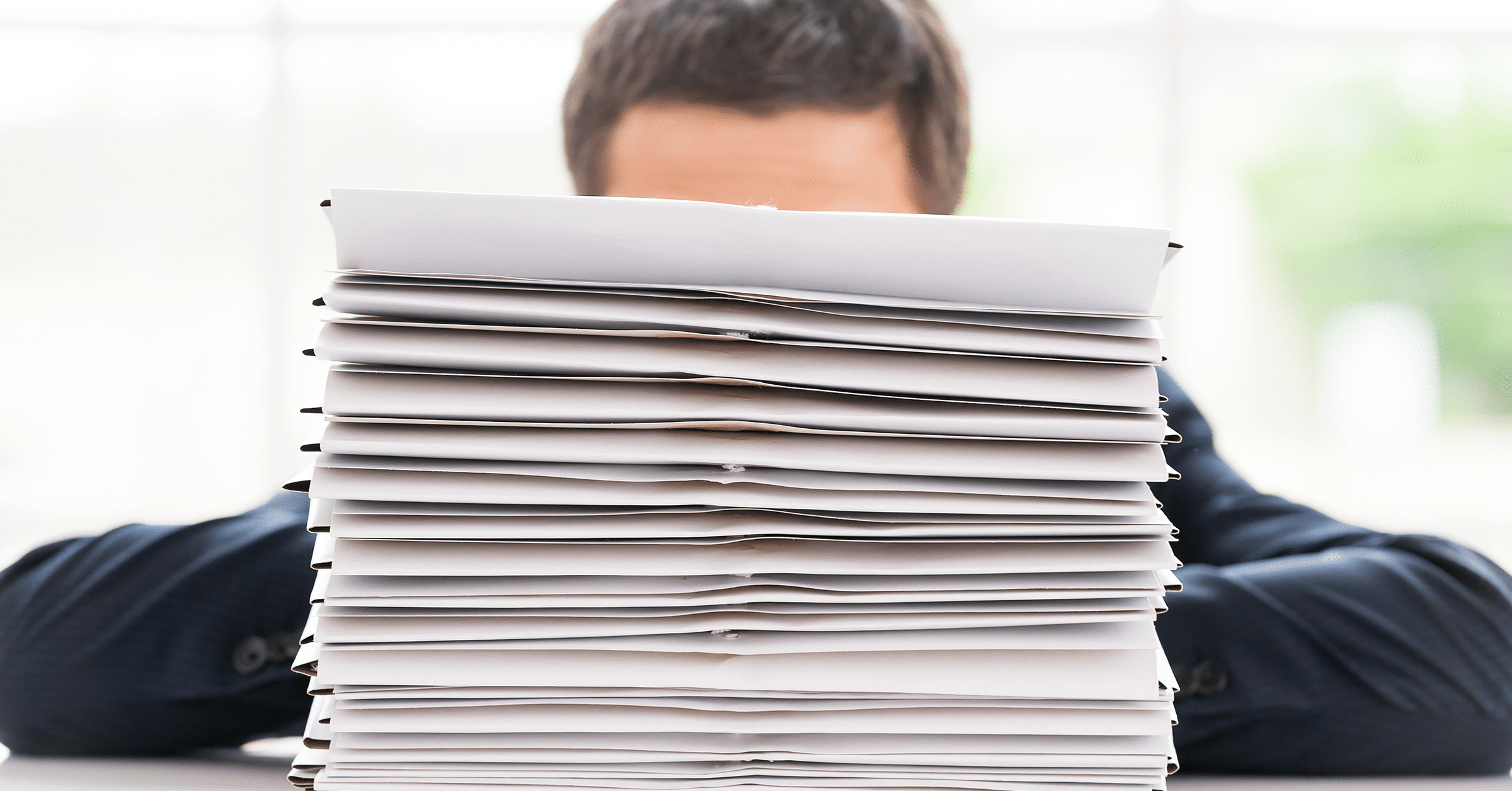 giant stack of papers covers man's face