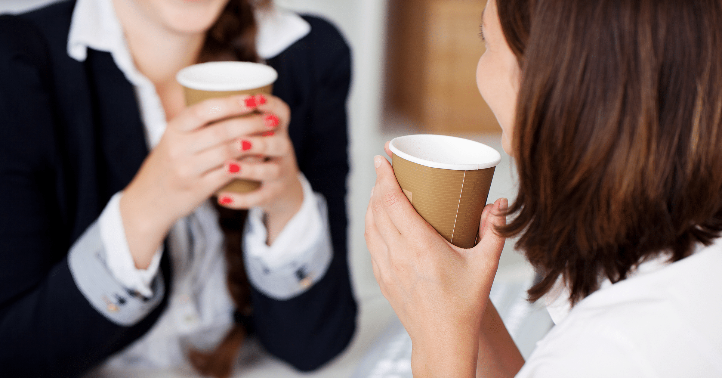 two women chat while drinking coffee