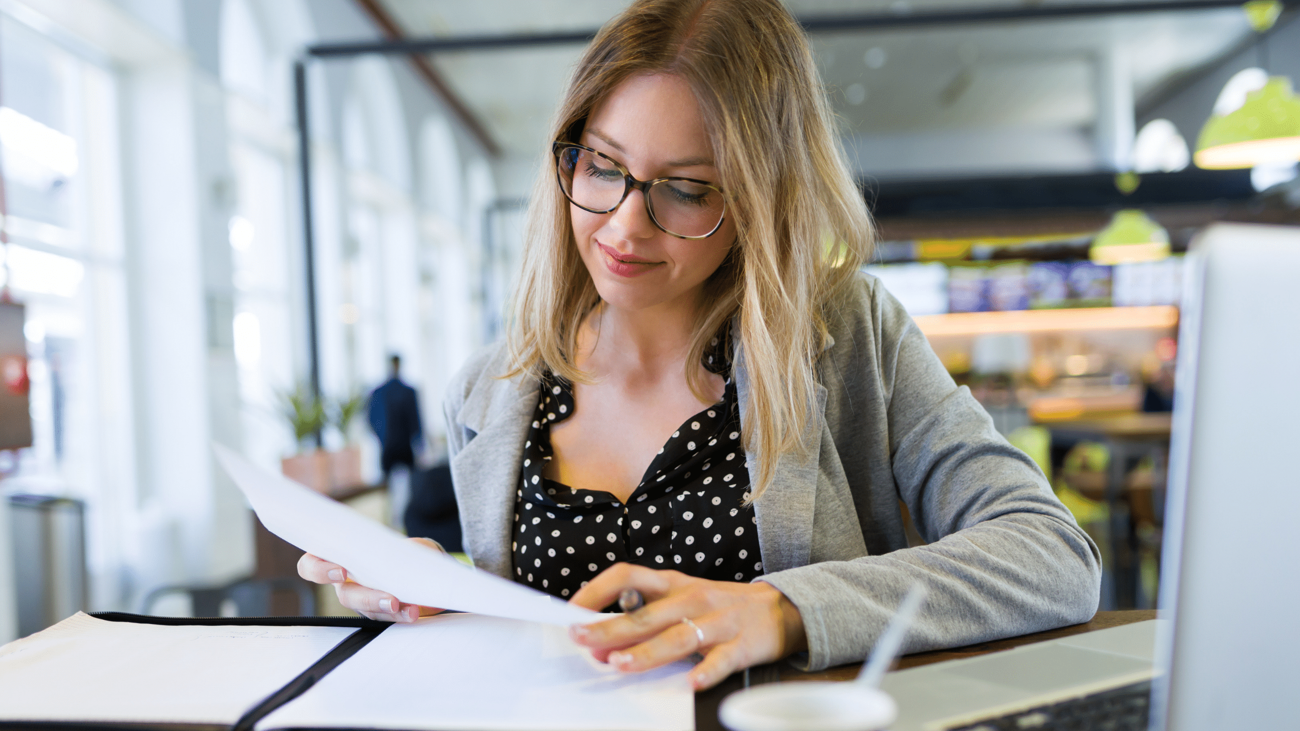 woman in office setting reviewing papers at her desk