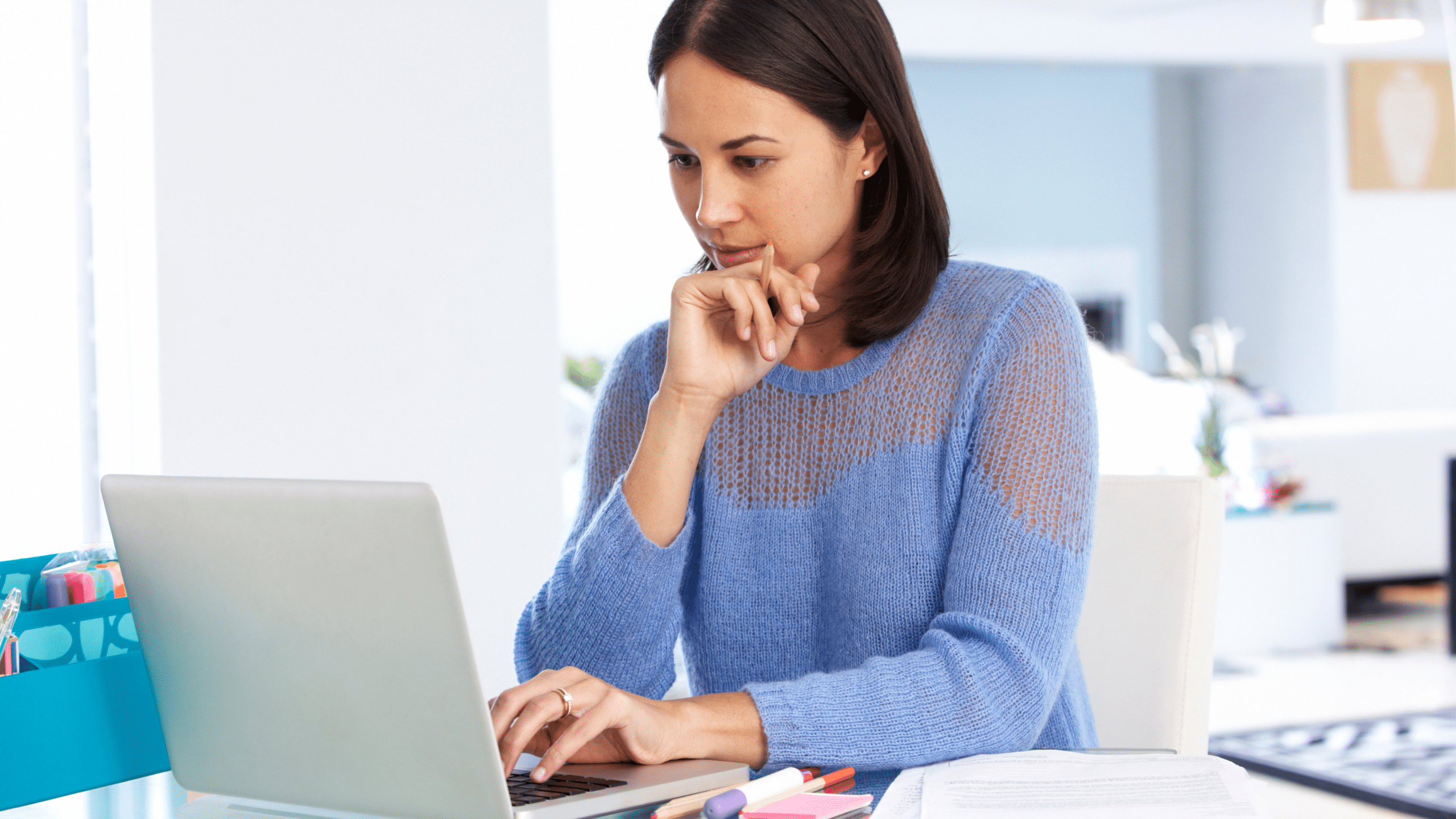 woman in blue sweater completing an online training on her laptop computer